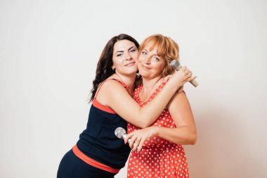 İki mutlu kadın mikrofonlara şarkı söylüyor ve eğleniyorlar.