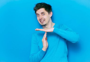 Bir adam, ellerin mola verdiğini gösterir. Gri bir arkaplanda.