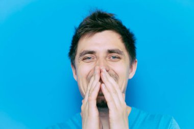 Adam gülüyor ve ağzını kapatıyor.