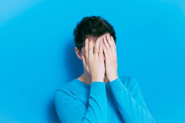 Adam elleriyle yüzünü örttü.