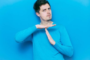 Bir adam, ellerin mola verdiğini gösterir. Gri bir arkaplanda.