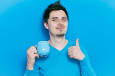 Stüdyonun arka planında fincan olan adam 