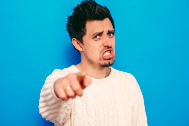 Genç adam işaret parmağını kameraya doğru gösteriyor.