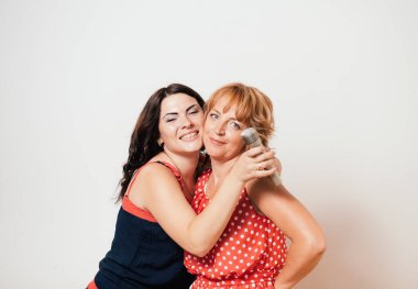 İki mutlu kadın mikrofonlara şarkı söylüyor ve eğleniyorlar.