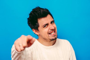 Genç adam işaret parmağını kameraya doğru gösteriyor.