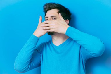 Adam gülüyor ve ağzını kapatıyor.