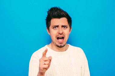 Genç adam işaret parmağını kameraya doğru gösteriyor.