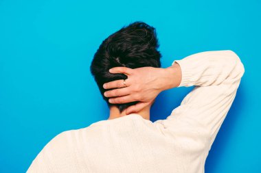 Kafasını tutarak. Arkadaki adam