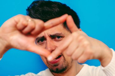 Stüdyonun arka planında el çerçevesi yapan adam. 