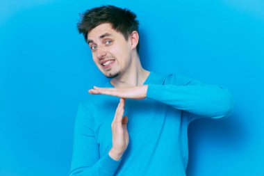 Bir adam, ellerin mola verdiğini gösterir. Gri bir arkaplanda.