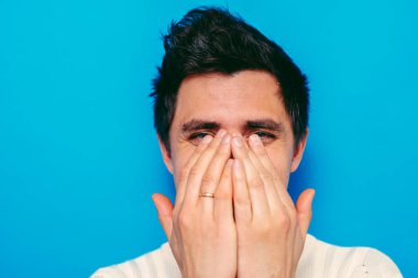 Adam gülüyor ve ağzını kapatıyor.