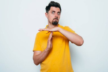 Bir adam, ellerin mola verdiğini gösterir. Gri bir arkaplanda.