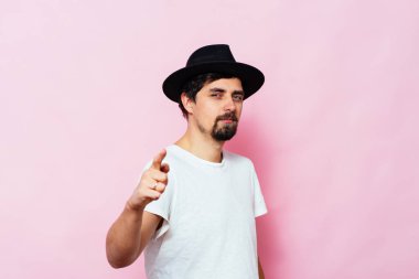 Genç adam işaret parmağını kameraya doğru gösteriyor.