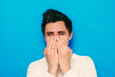 Adam gülüyor ve ağzını kapatıyor.