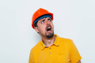 Miğferli adam, başını eliyle tutuyor.