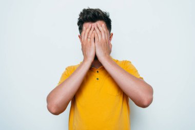 Adam elleriyle yüzünü örttü.