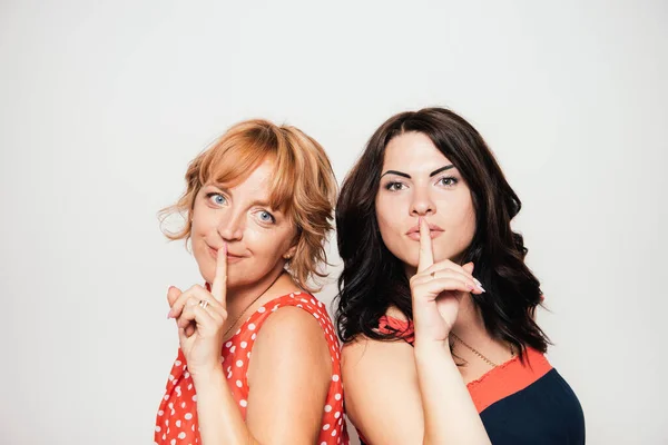 Portrait of two attractive women with finger on lips