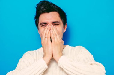 Adam gülüyor ve ağzını kapatıyor.