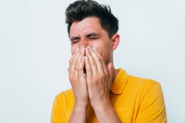 Adam gülüyor ve ağzını kapatıyor.