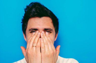 Adam gülüyor ve ağzını kapatıyor.