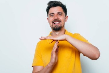 Bir adam, ellerin mola verdiğini gösterir. Gri bir arkaplanda.