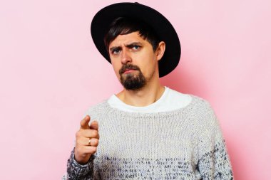 Genç adam işaret parmağını kameraya doğru gösteriyor.