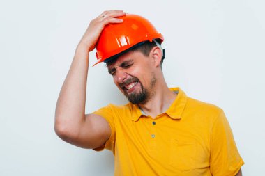 Miğferli adam, başını eliyle tutuyor.