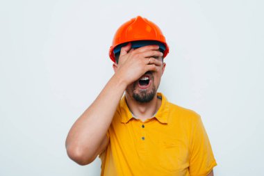 Miğferli adam, başını eliyle tutuyor.