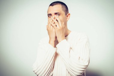 Adam gülüyor ve ağzını kapatıyor.