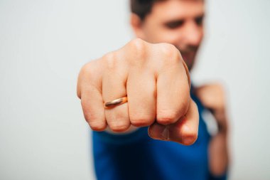 Boksör pozisyonunda duran ve yumruklarını sıkmaya hazır genç bir adamın yakın plan portresi.