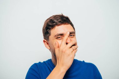 Adam gülüyor ve ağzını kapatıyor.