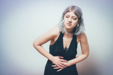 Stüdyo arka planında karın ağrısı olan kadın.
