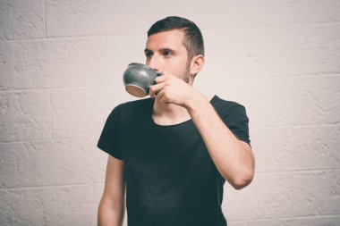 Stüdyonun arka planında fincan olan adam