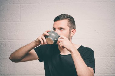 Stüdyonun arka planında fincan olan adam