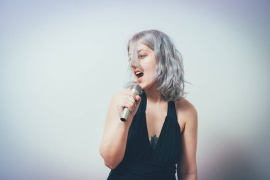 Genç kız mikrofonla şarkı söylüyor.