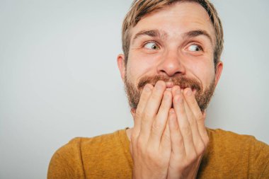 Adam gülüyor ve ağzını kapatıyor.