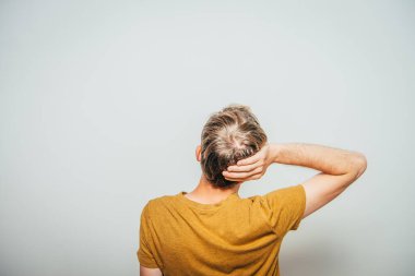 Genç adam. Arkadan bak. Gri bir arkaplanda