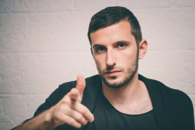 Genç adam işaret parmağını kameraya doğru gösteriyor.
