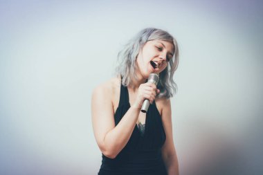 Genç kız mikrofonla şarkı söylüyor.