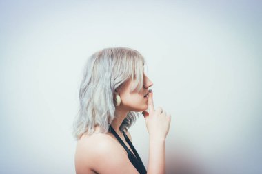 Kadın parmağını dudaklarına koydu.