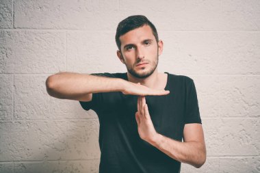 Bir adam, ellerin mola verdiğini gösterir. Gri bir arkaplanda.