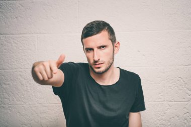 Genç adam işaret parmağını kameraya doğru gösteriyor.