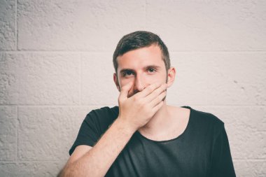 Adam gülüyor ve ağzını kapatıyor.