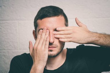  Adam elleriyle yüzünü kapatıyor.