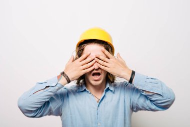 Miğferli işçi gözlerini kapatıyor.