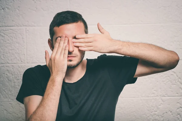 man covers his face by hand