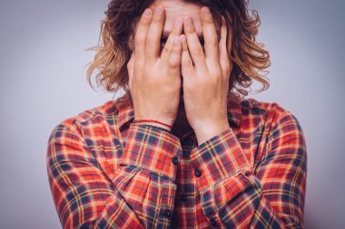 Adam elleriyle yüzünü örttü.