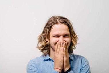 Adam gülüyor ve ağzını kapatıyor.