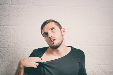 Delikanlının gömleği açarken çekilmiş portresi, çok sıcak. Negatif duygu, yüz ifadesi, his