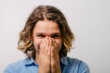 Adam gülüyor ve ağzını kapatıyor.